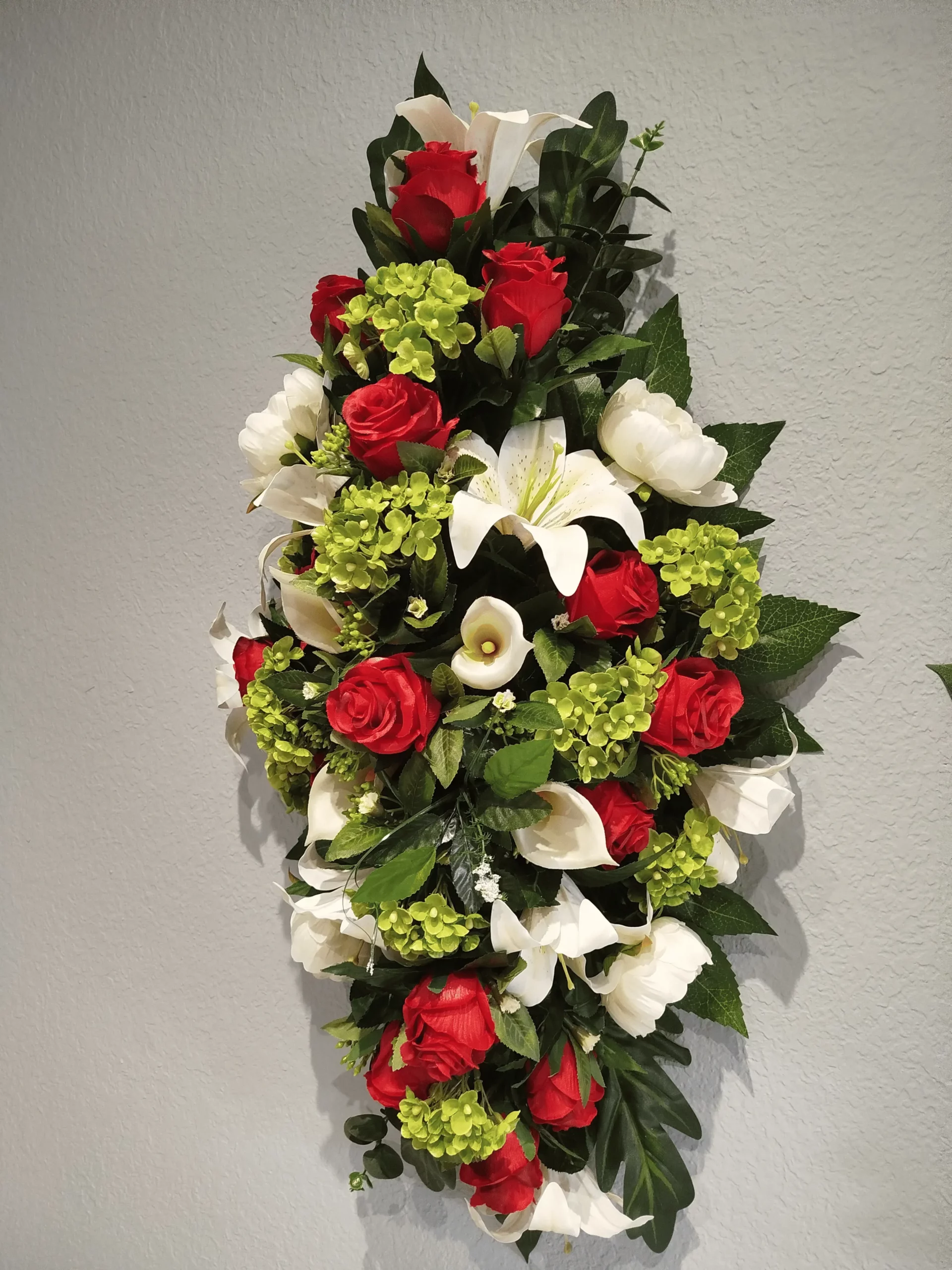 Grande gerbe de fleurs funéraire verticale avec roses rouges et lys blancs.