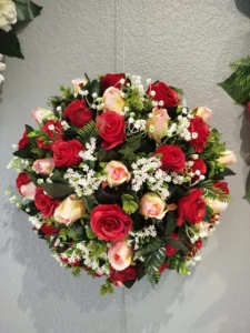Composition florale ronde de roses rouges et saumon avec gypsophile.