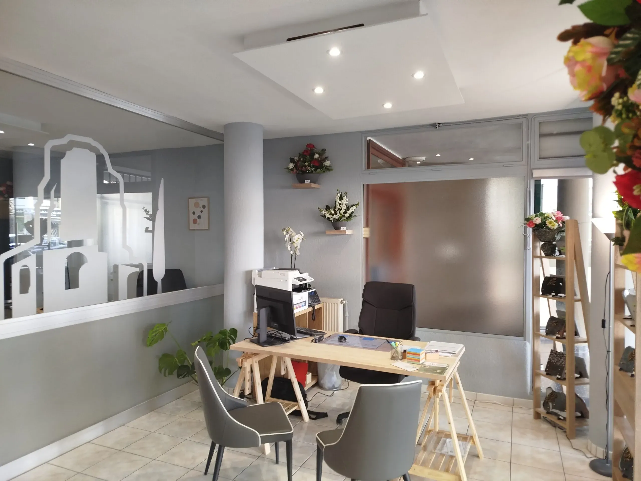 Bureau d'accueil funéraire moderne avec ordinateur et décoration florale.